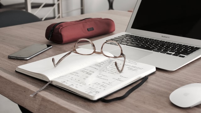 Glasses sitting on top of a notebook in front of an open laptop